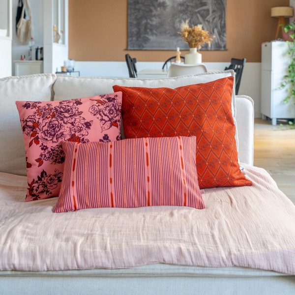 AIMI pink square cushion cover 40 x 40 cm, filled, on a sofa with other cushions from the collection